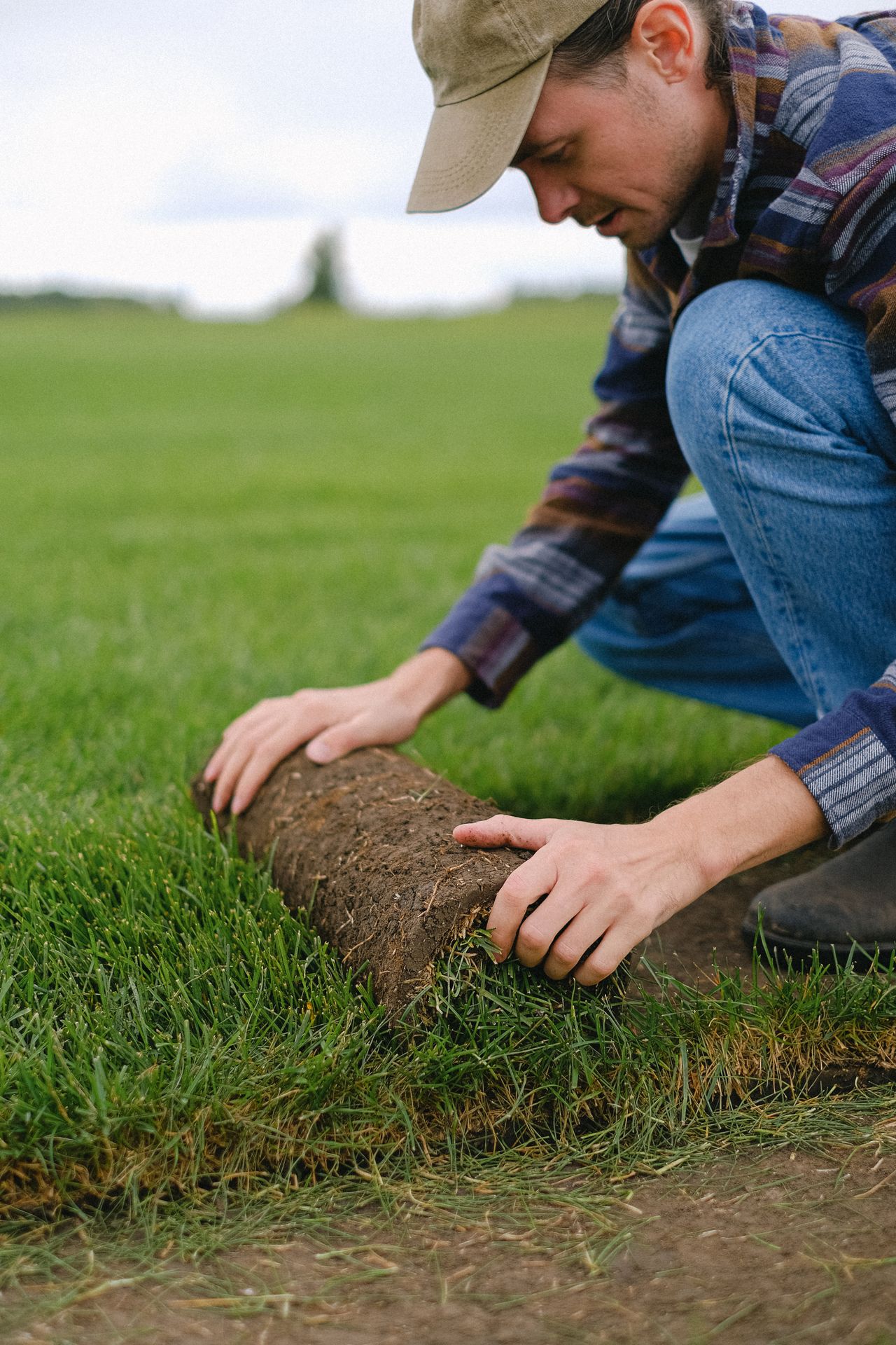 A worker laying turf on the ground
