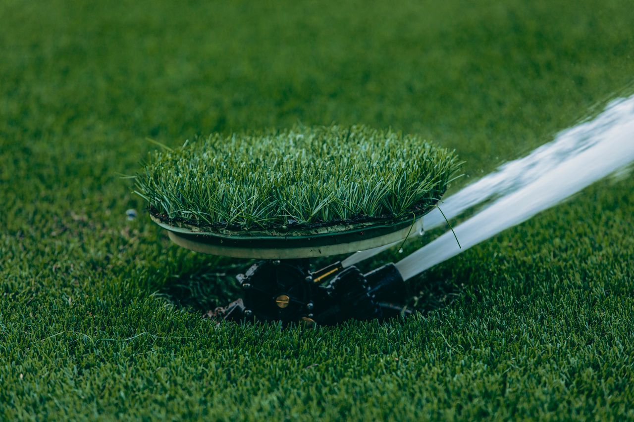 A sprinkler running over a green lawn